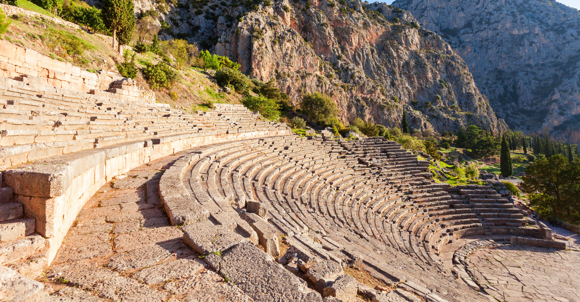 Ancient theater of Delphi with stone seating and mountain backdrop, historic site in central Greece