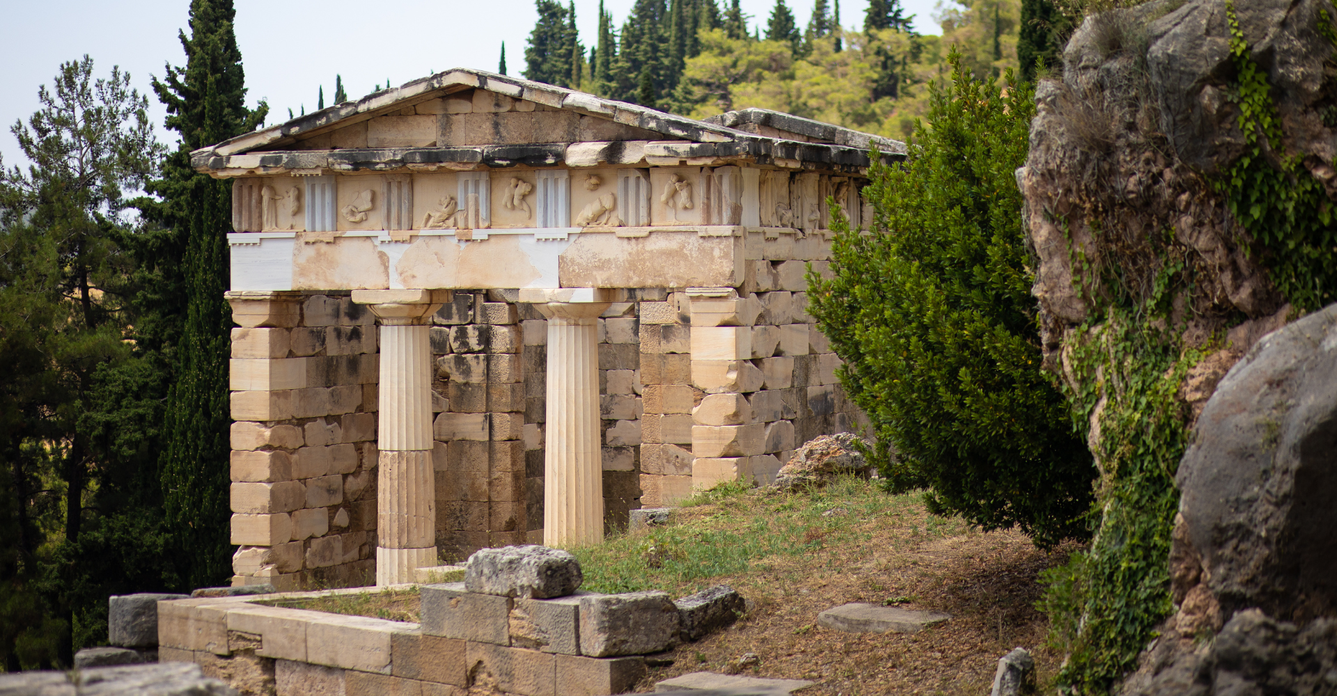 Ancient Treasury of the Athenians at Delphi archaeological site surrounded by trees, Greece