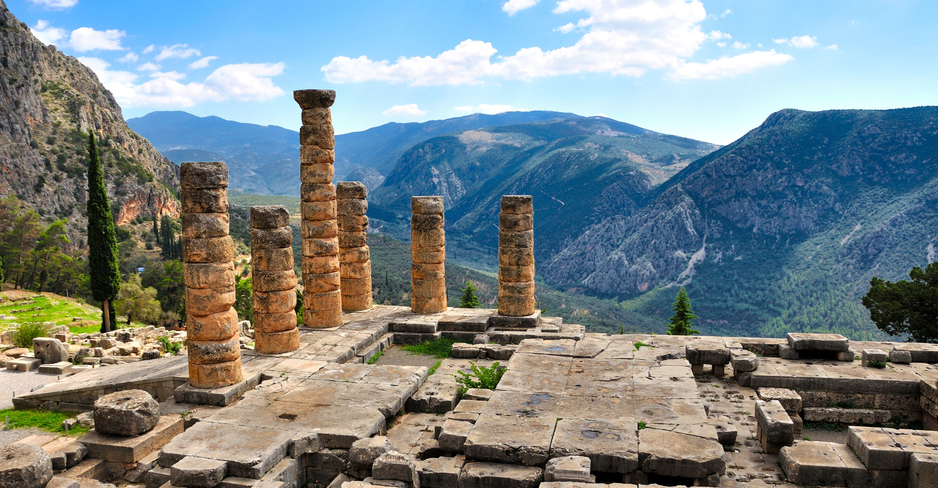 Ancient stone columns ruins with mountain landscape under blue sky in Delphi