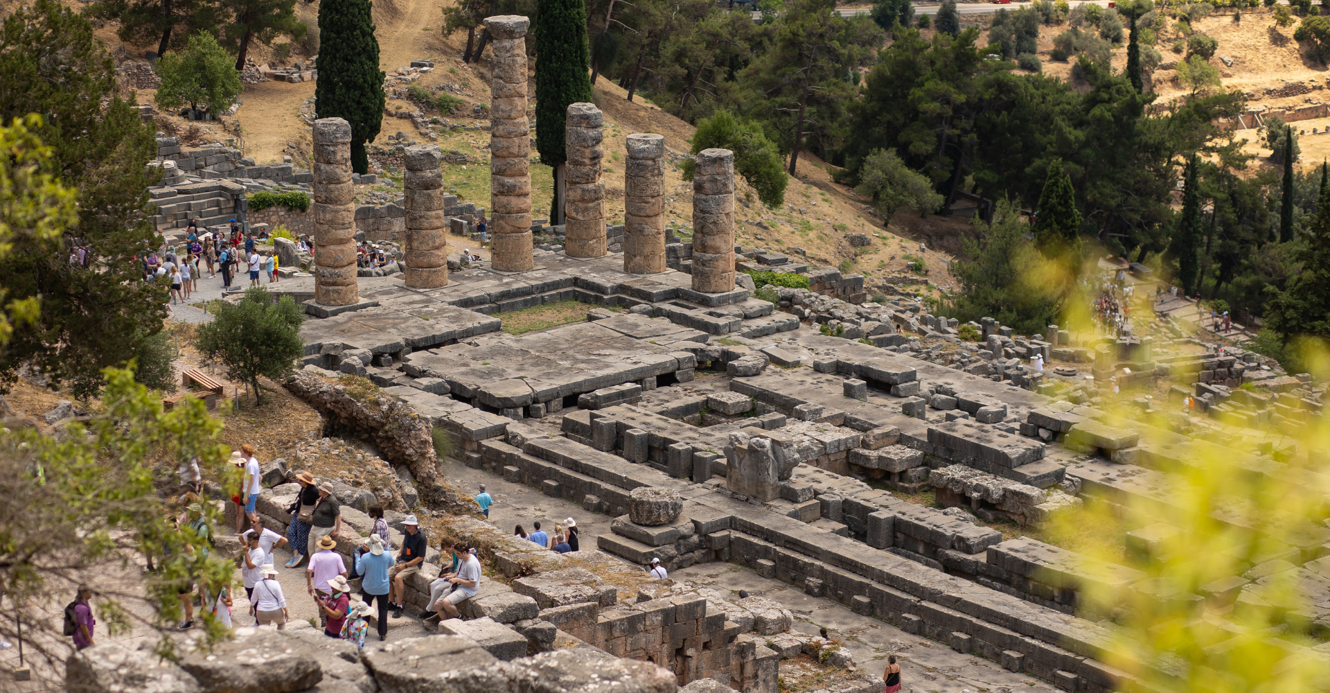 Aerial view of ancient Greek archaeological site with stone columns and tourists in Delphi