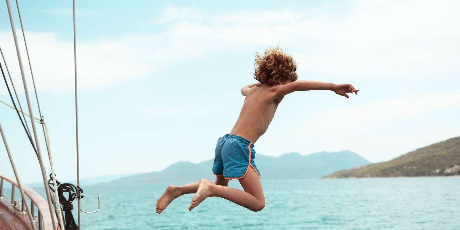A child that is diving to go for a swim at the cruise stop