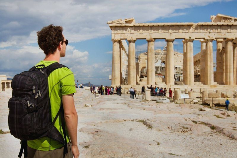 Backpacking traveler on the Acropolis site admiring the Parthenon